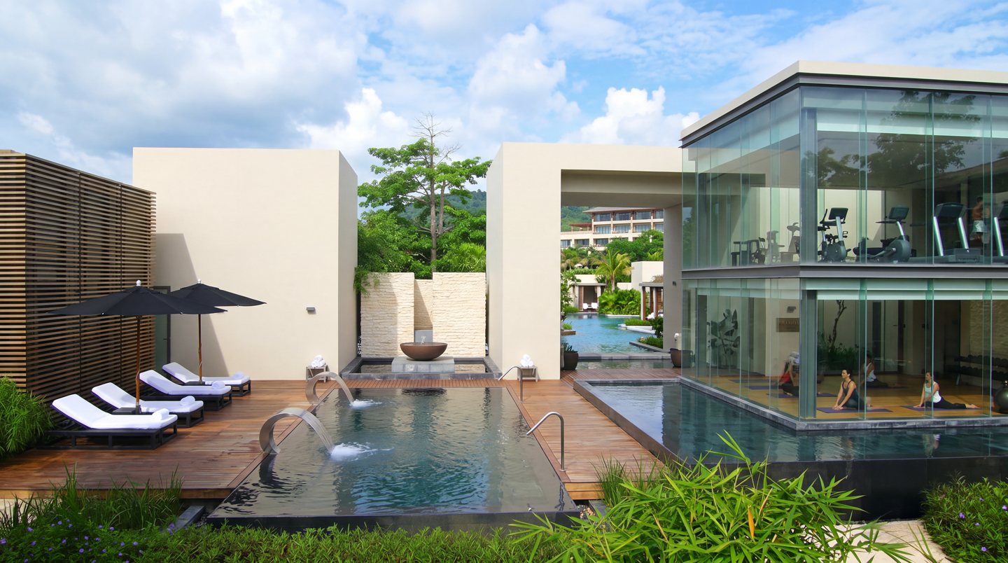 Concept image: a wellness center with a glass fitness and yoga studio, reflecting pools with water spouts and loungers on a timber deck